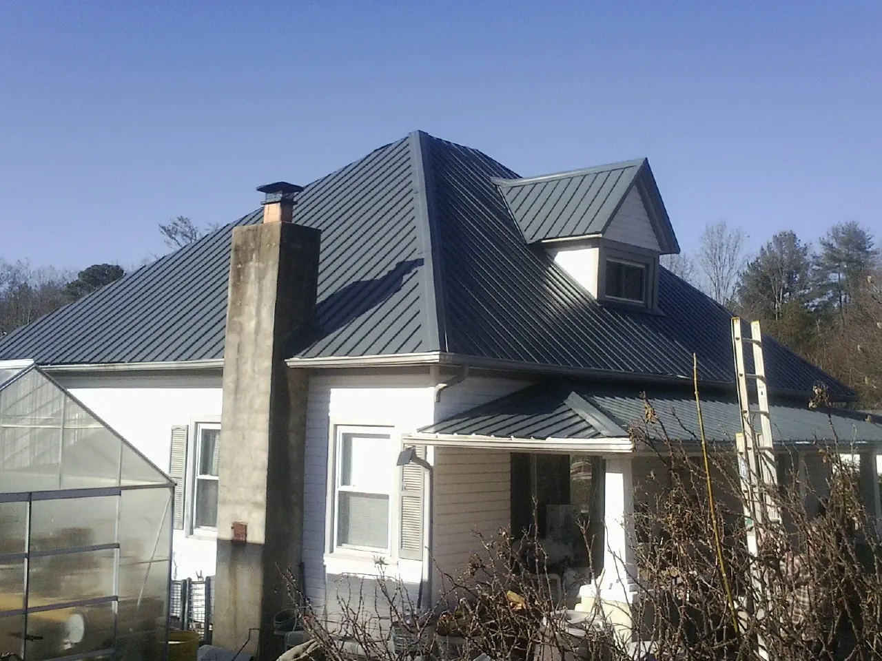 Dark blue standing seam metal roof on a white farmhouse with dormer — Slate & Tile Roof Repair by Roofing Brothers in Adger
