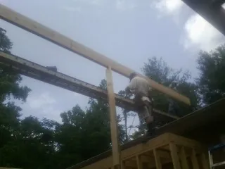Carpenter setting a ridge beam over a new addition frame — Ice Dam Removal by Roofing Brothers in Adger