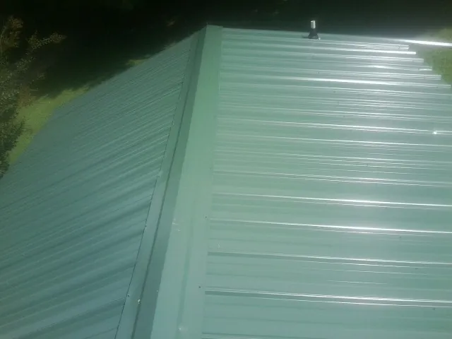 New green metal panels meeting at the ridge of a roof — Flat Roof Repair work by our crew in Adger