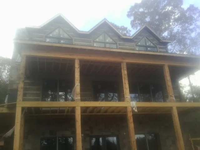 Dormers and porch framing on a large log home under construction — Roof Coating work by our crew in Adger