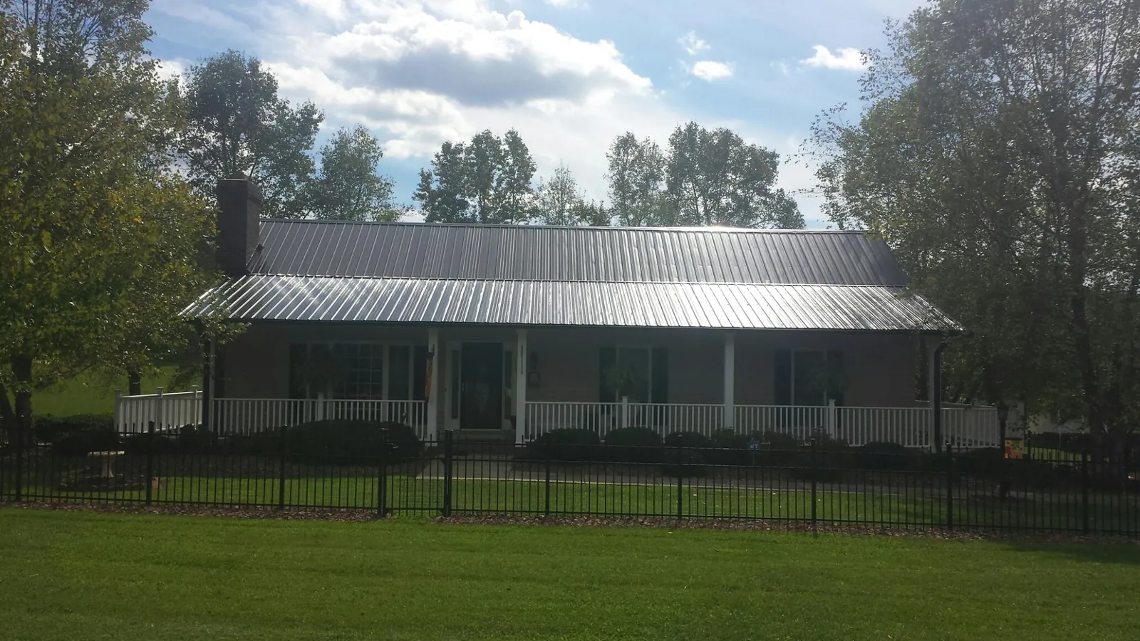 Gray metal roof on a brick ranch with a full width front porch — Gutter Guard Installation work by our crew in Adger