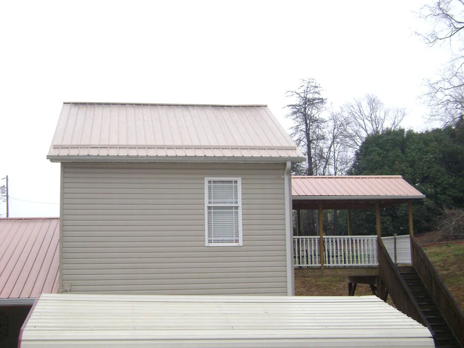 Tan metal roofs on a two story addition and attached porch, from a Roof Replacement job in Adger
