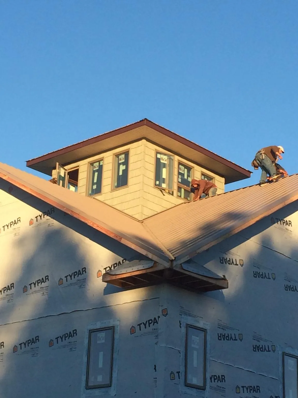 Roofers working around a rooftop cupola on a new metal roof at sunset — Roof Waterproofing in Adger by Roofing Brothers